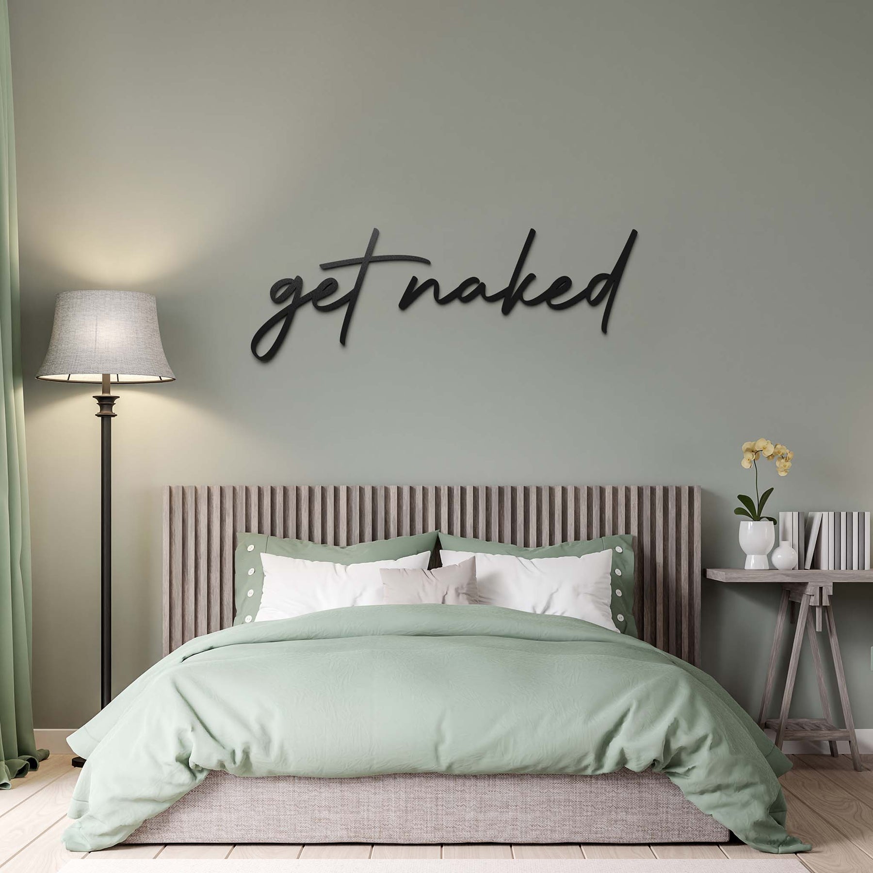 Mesi Get Naked Wanddekoration in einem Schlafzimmer ueber einem Holzbett mit gruenen Lacken an einer gruenen Wand